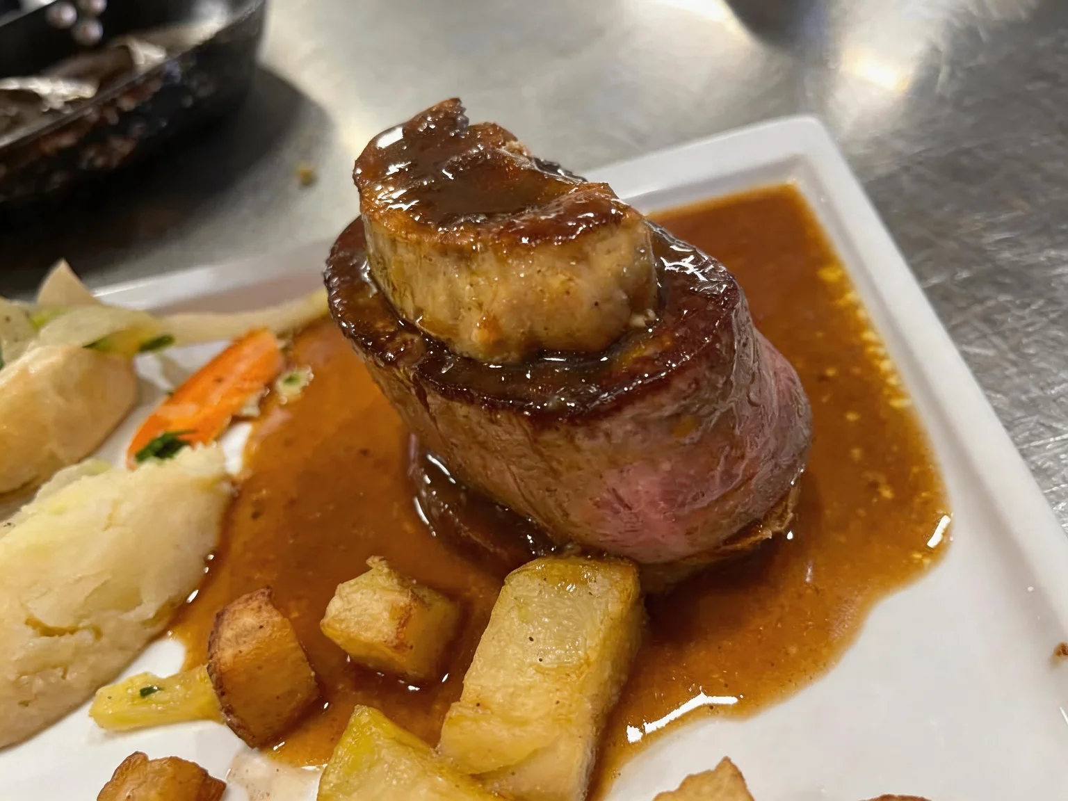 Sliced beef fillet with sauce, topped with a seared slice of foie gras.