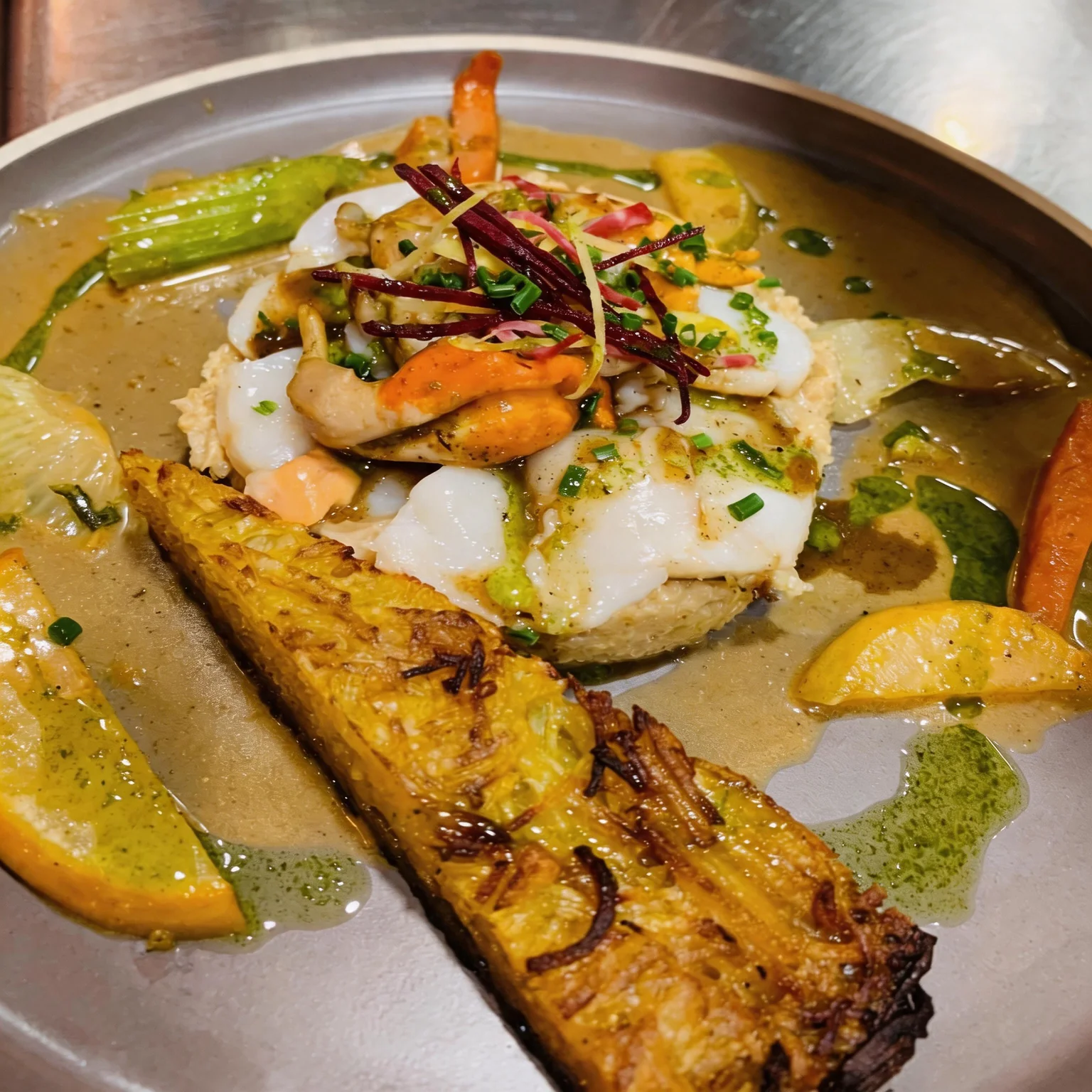 Seafood and fish over a bed, served with a crispy potato cake.